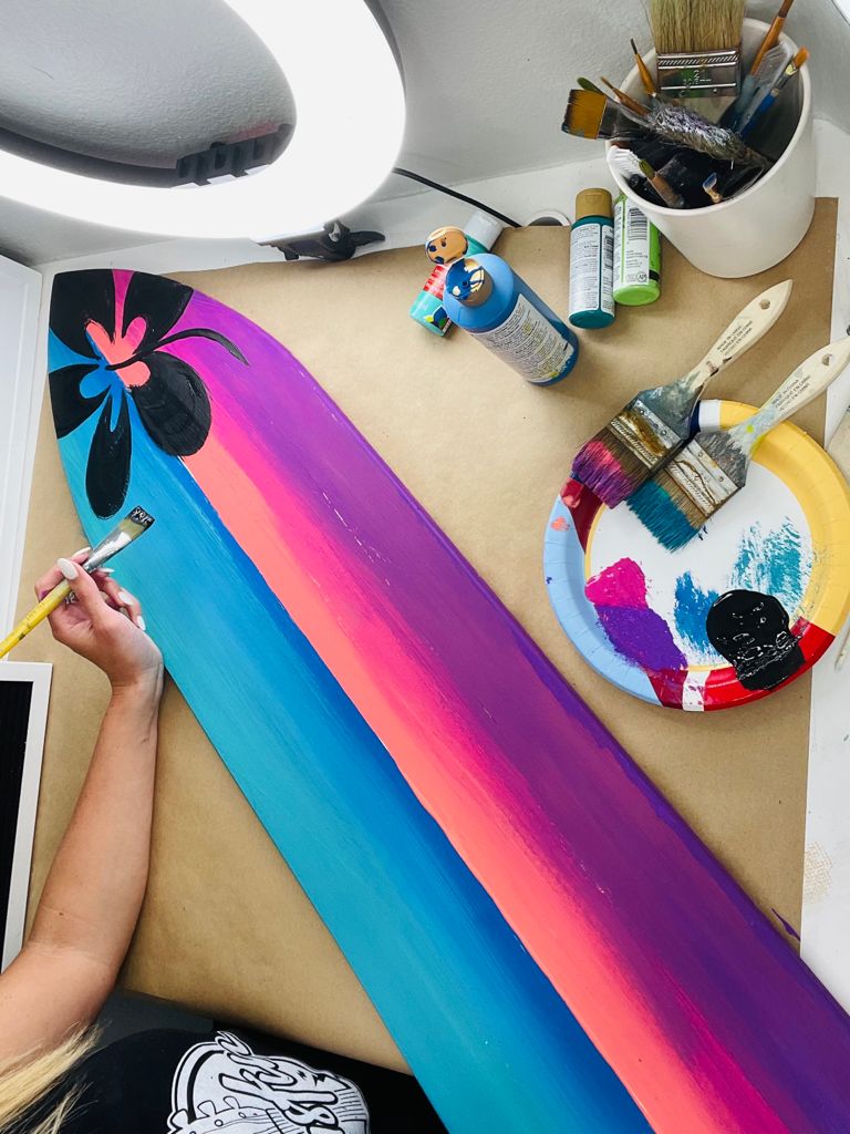 colorful decorative surfboard with hibiscus and art supplies