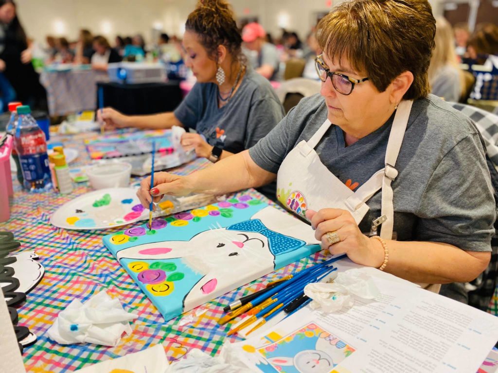 Women painting an easter bunny canvas at a paint party